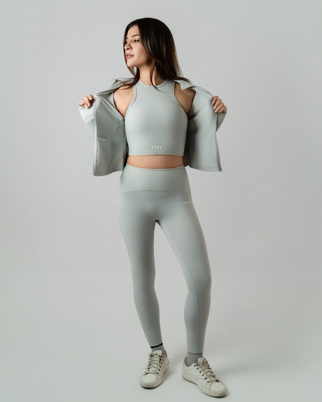 Woman wearing a light gray athletic outfit on a plain background